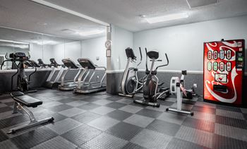 A gym with a variety of exercise equipment including treadmills, stationary bikes, and weight machines